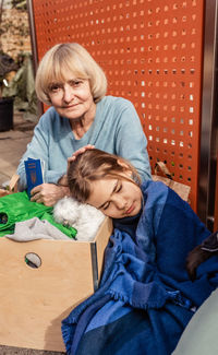 Senior refugee woman holding ukrainian passports sitting with little girl at charity center 