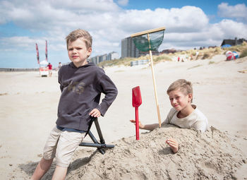 Portrait of happy boy playing on beach against sky