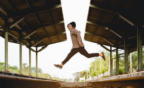 Low angle view of young man jumping against built structure