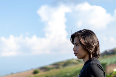 Side view of woman looking away against sky