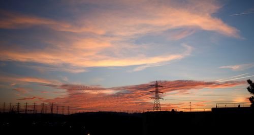 Low angle view of silhouette electricity pylon against sky during sunset