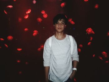 Portrait of young man standing against aquarium