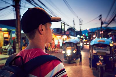 Rear view of young man walking on street at dusk