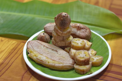 Grilled banana with dipping sauce on wooden table.