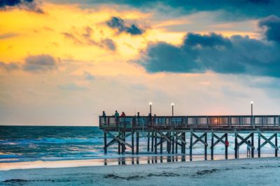 Pier over sea against sky during sunset