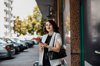 Portrait of smiling young woman standing in city