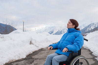 Caucasian woman in a wheelchair travels in the mountains in winter