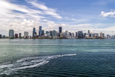 Sea by cityscape against sky