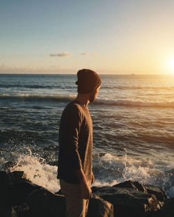 Woman looking at sea against sky during sunset