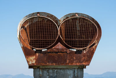 Low angle view of rusty metal against clear blue sky