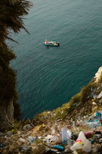 High angle view of boats in sea with garbage visible in the foreground.