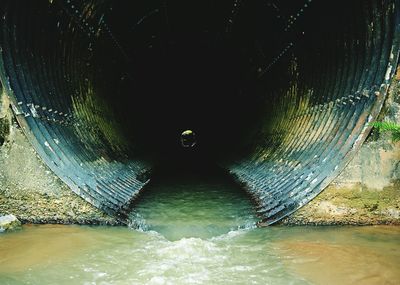 Water flowing through tunnel under bridge