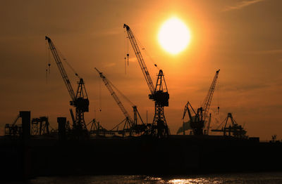 Low angle view of crane against sunset