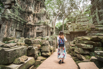 Rear view of woman with backpack walking outside temple