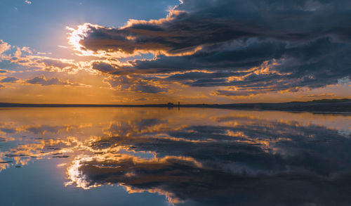 Scenic view of sea against dramatic sky during sunset