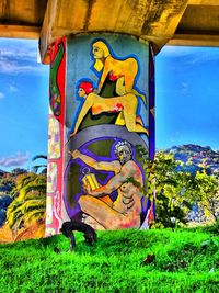 Close-up of graffiti on grass against blue sky