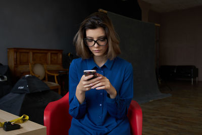 Young woman using mobile phone while sitting on chair