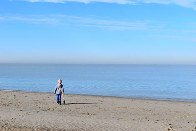 Rear view of woman on beach against sky