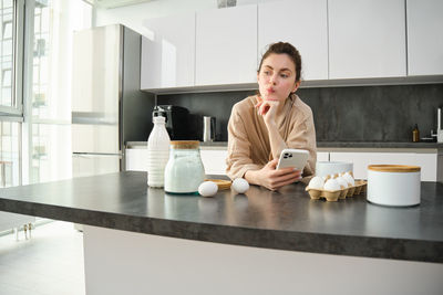 Young woman using mobile phone while sitting on table