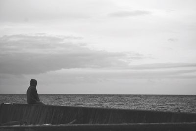 Rear view of man standing by sea against sky