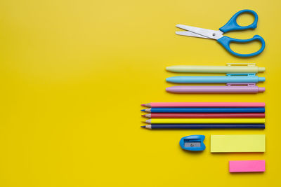 Directly above shot of school supplies on yellow background