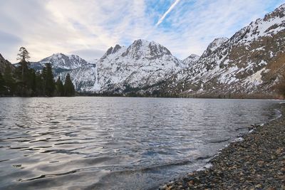 Scenic view of lake by snowcapped mountains against sky