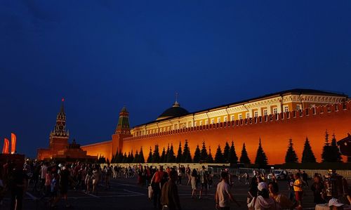 Group of people in front of building against clear blue sky