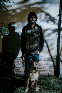 Man with dog standing against wall