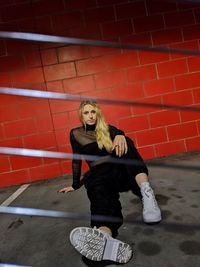 Portrait of young woman standing against brick wall