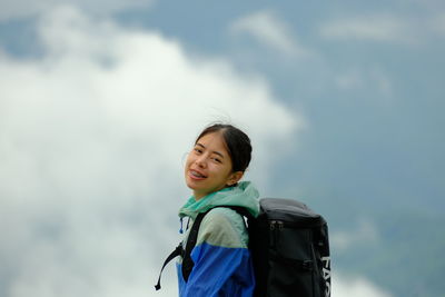 Young woman standing against sky