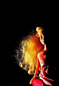 Portrait of woman with illuminated hair against black background