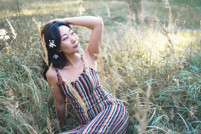 Side view of young woman standing against plants