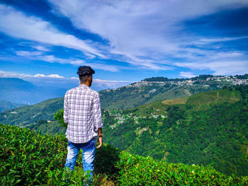 Rear view of man looking at mountain against sky