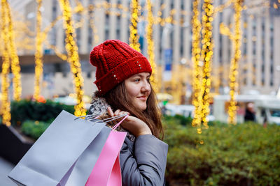 Portrait of young woman holding hat against blurred background