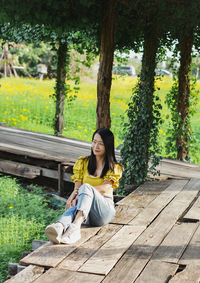 Full length of young woman sitting on boardwalk