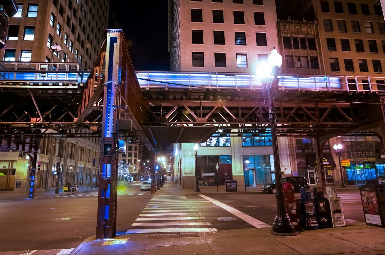 architecture, built structure, building exterior, the way forward, city, illuminated, street light, transportation, street, incidental people, night, diminishing perspective, bridge - man made structure, building, connection, city life, outdoors, lighting equipment, railing, sidewalk