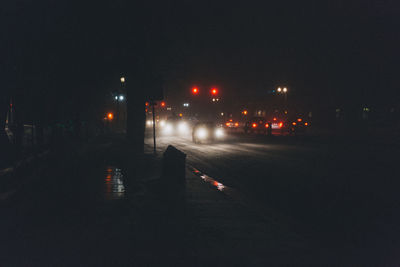 Illuminated city street against sky at night