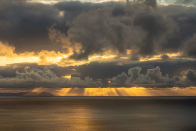 Scenic view of sea against dramatic sky during sunset