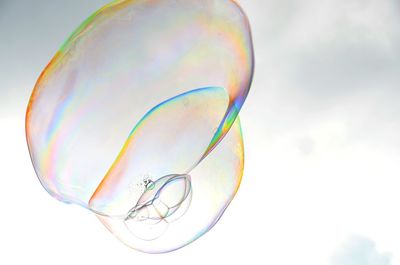 Low angle view of bubbles in mid-air against sky