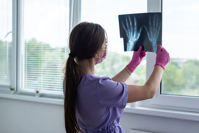 Side view of young woman holding window