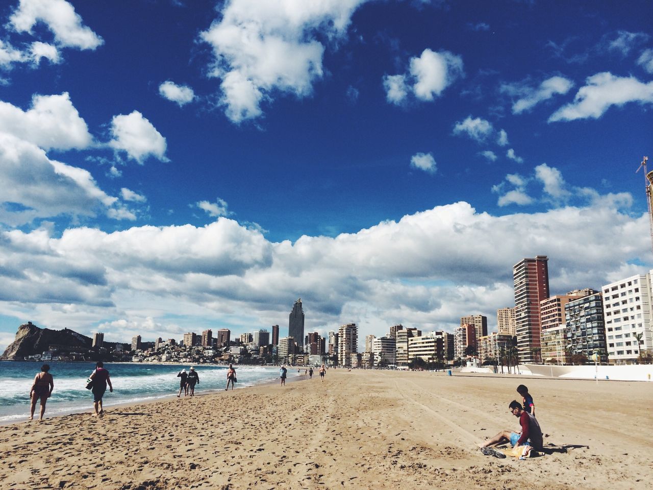 beach, sky, men, leisure activity, lifestyles, sand, architecture, built structure, person, large group of people, building exterior, shore, water, cloud - sky, vacations, sea, city, mixed age range, tourist