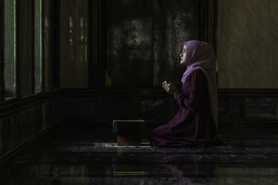 Side view of young woman sitting at home