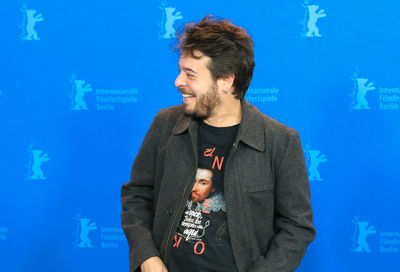 Close-up of smiling young man standing against blue wall