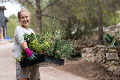 Woman working in the garden carrying plants in the container