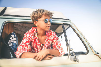 Close-up of boy in car against sky