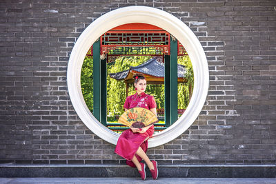 Portrait of woman standing against brick wall