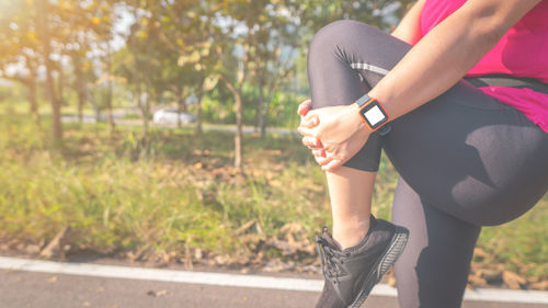 Low section of woman exercising against trees