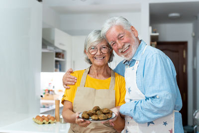 Portrait of senior female friends holding food at home