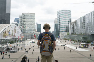 Rear view of man on street against buildings in city