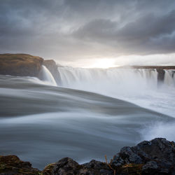 Scenic view of waterfall against sky